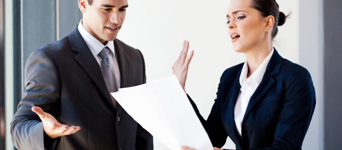 two young colleagues arguing over paperwork in office