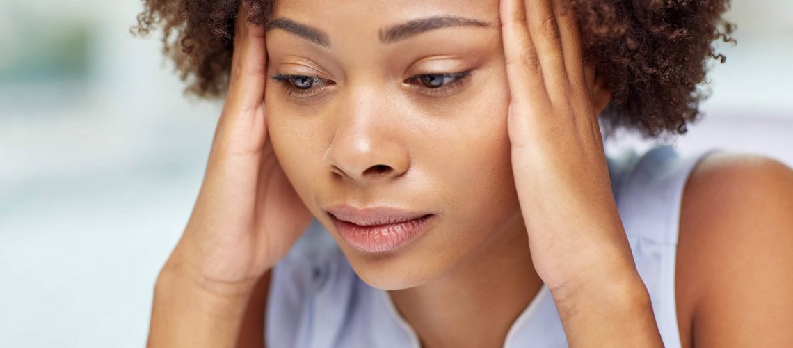 close up of african young woman touching her head people, emotions, stress and health care concept - unhappy african american young woman touching her head and suffering from headache